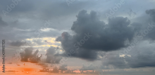 Bild auf Leinwand Clouds gather over a horizon at sunset with hints of orange and gray colors agai