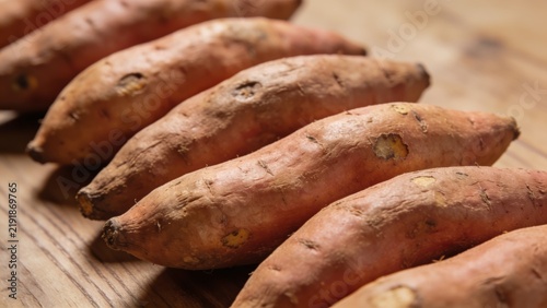 Sweet potatoes tubers aligning on rustic wooden table