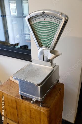 Bild auf Leinwand Vintage mechanical counter scales made of metal on a wooden block stand, retro grocery weighing machine close up