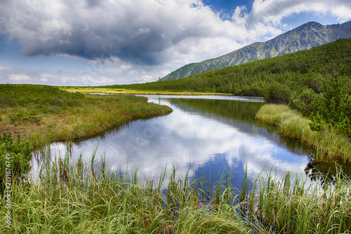 Türkisfarbener Bergsee vor majestätischer Felslandschaft und bewölkten Gipfeln