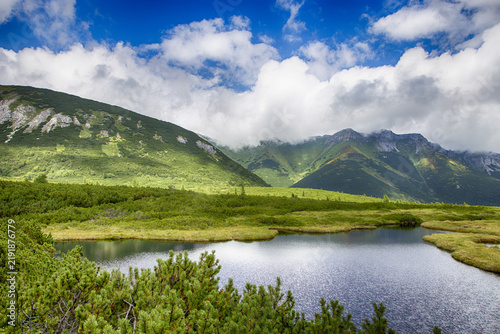 Türkisfarbener Bergsee vor majestätischer Felslandschaft und bewölkten Gipfeln