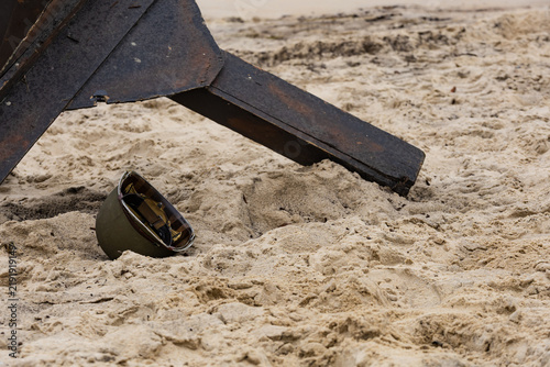 Фотография An American infantry helmet from World War II lies on the beach next to a czech
