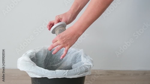 The woman is cleaning the vacuum cleaner filter of debris and dust.