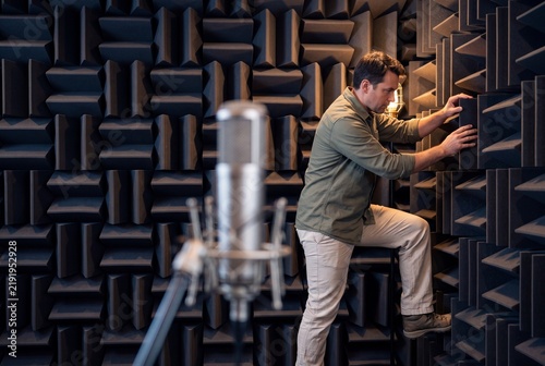 Acoustic Engineer Inspecting Soundproofing Foam Panels Inside an Anechoic Testing Chamber with Studio Microphone