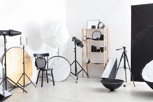 Different modern lighting equipment and chair in photo studio