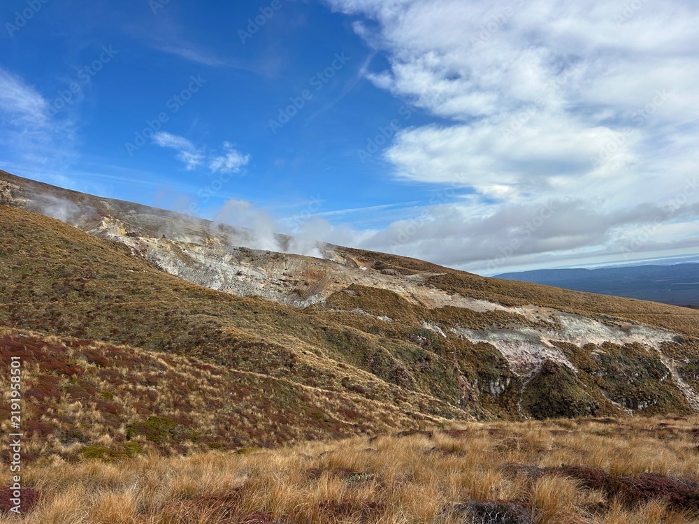 Fototapeta premium Mountain landscape with drifting clouds near the end of the Tongariro Alpine Crossing in Tongariro National Park, New Zealand.
