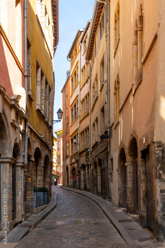 Fototapeta premium Charming cobblestone alleyway lined with historic colorful buildings in Lyon