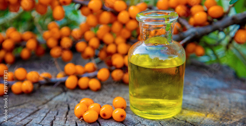 Quadro su tela Sea buckthorn oil in glass dropper bottle with fresh ripe berries