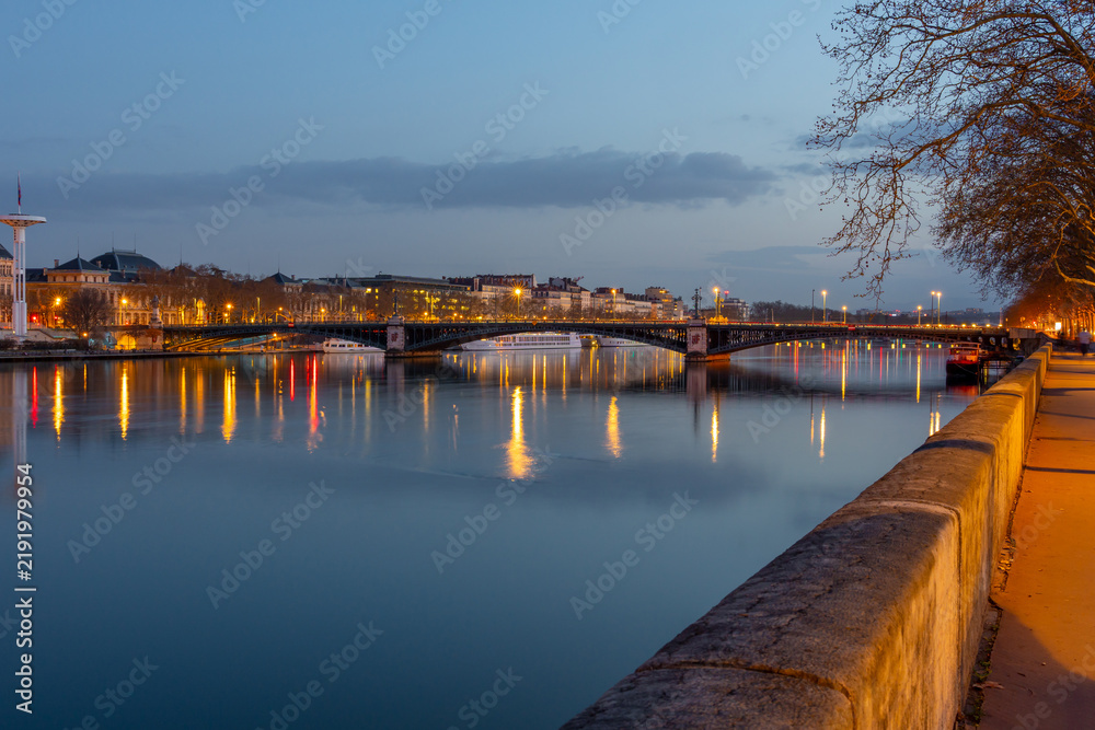 Fototapeta premium Lyon cityscape at dusk with river reflections and illuminated bridge