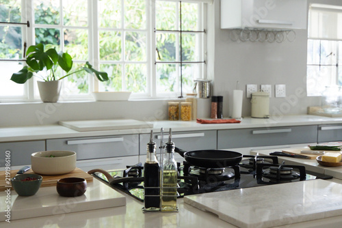 Gas cooktop with black frying pan and oil bottles sitting on island with cutting boards, cheese