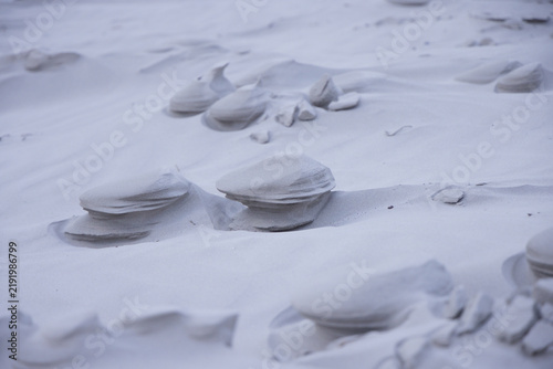 Sand pedestals are rising on dune field with pebbles, low ripples and soft diffuse light