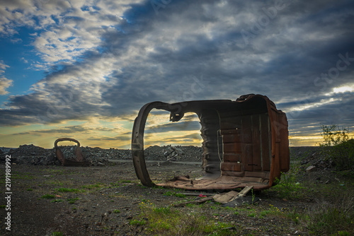 A broken excavator bucket lies in a pile of waste iron ore.