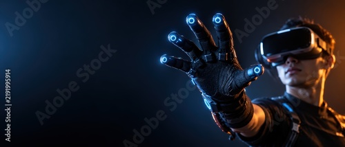 Man Wearing VR Headset and Smart Haptic Glove with Glowing Sensors Reaching Forward