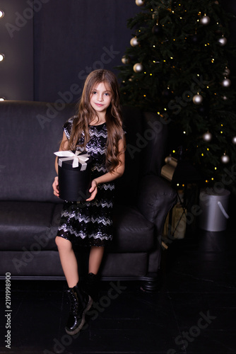 Girl in Sequined Dress Holding Gift Box Near Christmas Tree