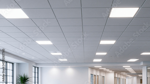 Modern office ceiling with bright led light panels and acoustic tiles. Commercial interior design background for architectural concepts.