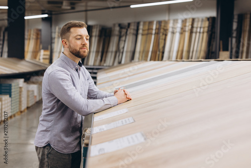 Man shopping for home renovation materials  inspecting samples of flooring  making decisions for interior design