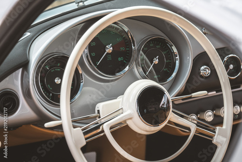 Vintage car dashboard with classic white steering wheel and gauges
