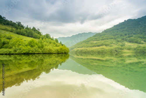 Scenic Mountain Lake Landscape with Green Hills Reflection Under Cloudy Sky