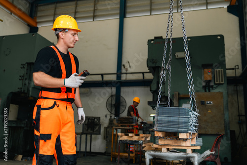 Foto Industrial worker in safety helmet and reflective clothing guiding suspended ste