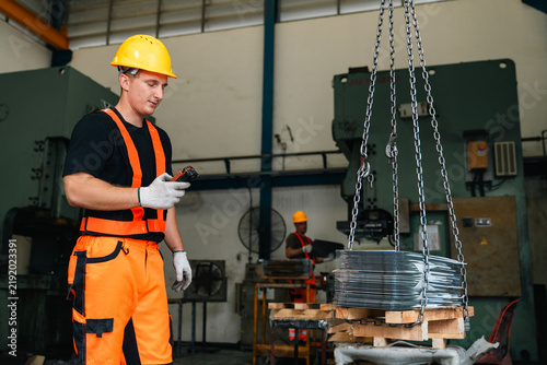 Obraz na plátne Industrial worker in safety helmet and reflective clothing guiding suspended ste