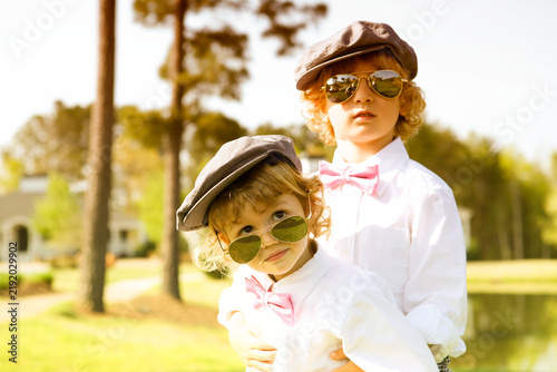 Foto Two Stylish Young Boys Wearing Tweed Hats, Sunglasses and Bow Ties at Sunset