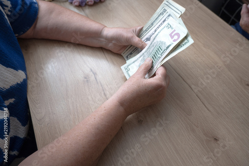 A woman is counting money—US dollars.
