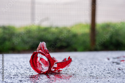 A broken red grave candle on the asphalt in the rain