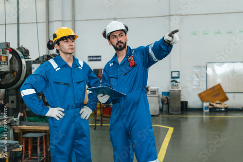 Photography Industrial workers in blue coverall and safety helmet inspecting factory floor w
