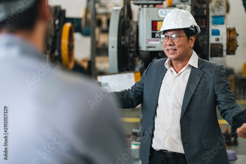 Foto Industrial engineer safety helmet discussing machinery with worker manufacturing