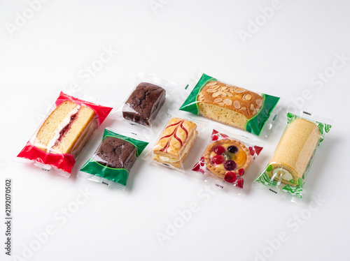 Assorted individually packaged cakes pastries and snacks on white