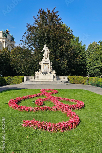 A wonderful photo of a Mozart statue with flowers arranged to form a musical clef, taken in Vienna on a beautiful day