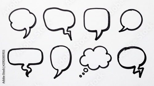 Set of eight hand drawn speech bubbles and thought clouds with black ink outline on a simple creative page