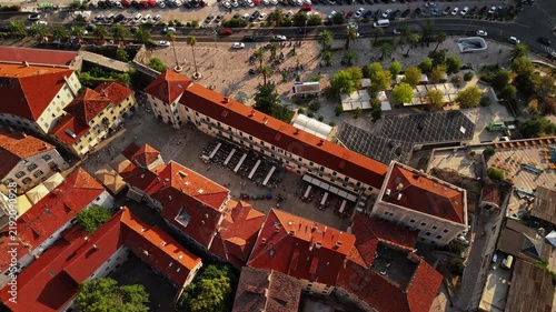 kotor, montenegro - aerial top down view of the main square of kotor old town with its stone clock tower, market canopies, cafe seating and the palm lined promenade beyond