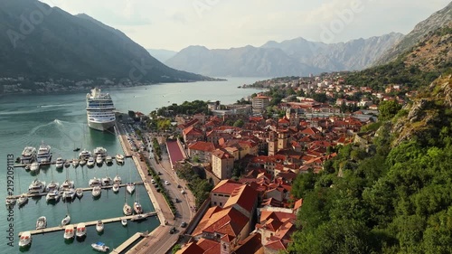 kotor, montenegro - aerial reveal pushing between two ruined stone towers of the kotor fortress to open onto the full bay of kotor with hazy layered ridges and the town below