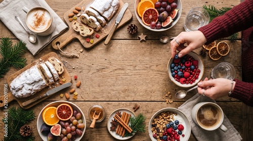 Festive Christmas breakfast spread with stollen, fresh berries, fruit, granola, and coffee on a wooden table