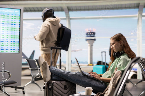 Foto Digital nomad woman waits for an airplane flight in an international airport terminal, showing freedom to work anywhere and a flexible location-independent career in air travel and remote work