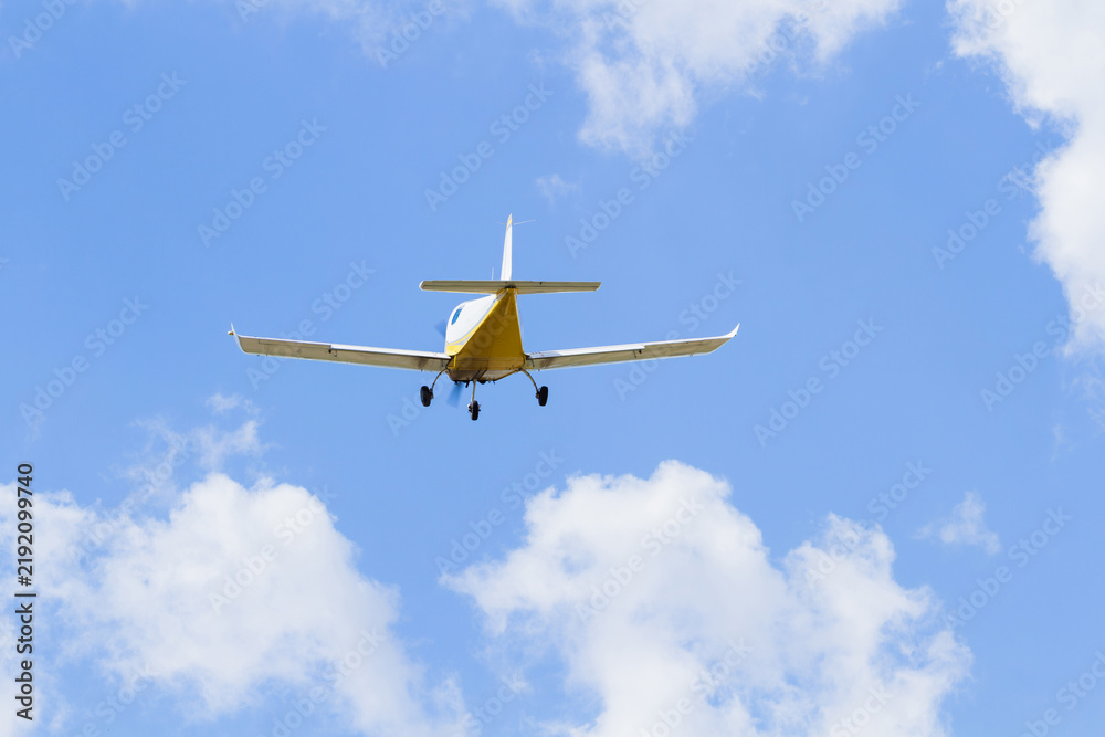 Fototapeta premium Small airplane flying through a blue sky | Mały samolot lecący na tle błękitnegp nieba