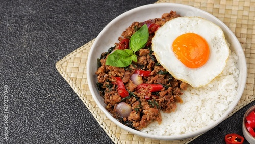 Pad kra pao, a popular Thai stir-fried dish made with minced meat, fragrant holy basil, garlic, and chili, served with steamed jasmine rice and often topped with a crispy fried egg. A flavorful and ar
