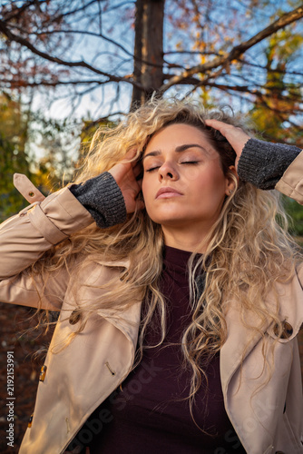 Cuadro en lienzo A young woman with curly blonde hair relaxes with her eyes closed while gently h
