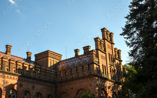 Foto The ornate brick facade and tiled roof of Chernivtsi University under warm sunli