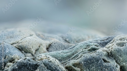 Extreme close up of textured grey river stones showcasing natural geological formations and weathered mineral details in soft lighting