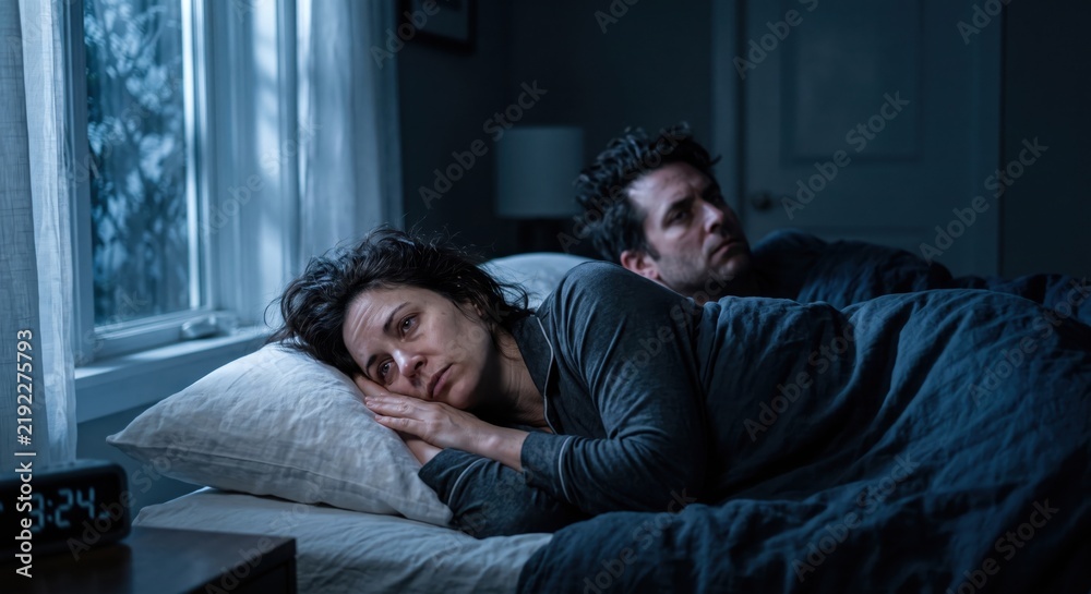 Fototapeta premium Worried sleepless couple lying awake in bed at night with a digital clock showing 3 AM