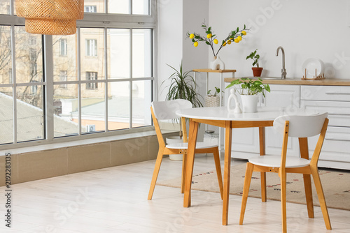 Interior of light kitchen with counters, dining table and window