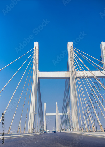 Suspension bridge with tall pylons and steel cables crossing highway under blue sky Cairo