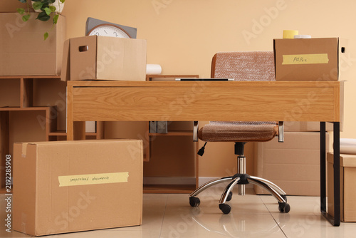 Fotografie Corporate downsizing and office relocation, cardboard boxes on desk with empty c