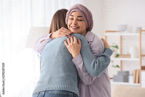 Beautiful woman after chemotherapy hugging her daughter at home. Brain cancer...