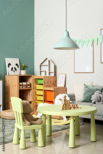 Interior of childrens room with table, toys and sofa