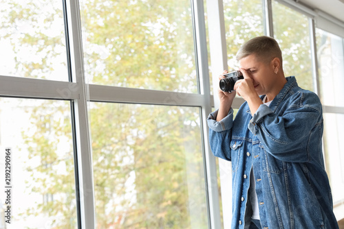 Young woman with short hair and photo camera near window at home