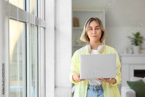 Beautiful woman with laptop near window at home
