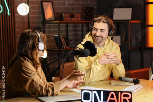 Couple of radio presenters recording at table in studio